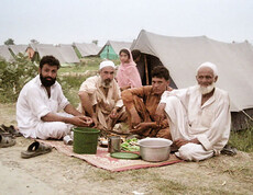 Männer in Pakistan beim Essen in ihrem Zeltdorf