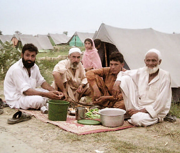 Männer in Pakistan beim Essen in ihrem Zeltdorf