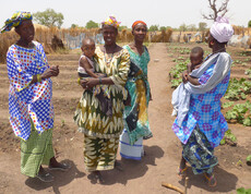 Frauen mit ihren Kindern stehen in einem landwirtschaftlichen Projekt in der Region Tambacounda, Senegal.
