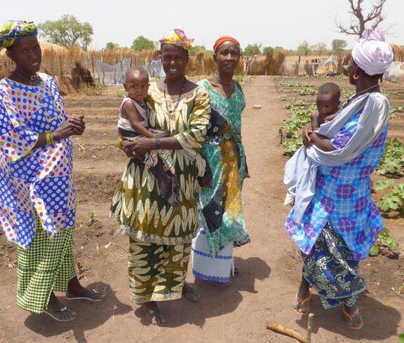 Frauen mit ihren Kindern stehen in einem landwirtschaftlichen Projekt in der Region Tambacounda, Senegal.