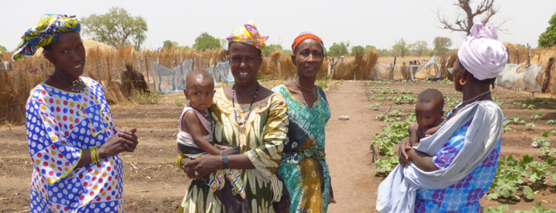 Frauen mit ihren Kindern stehen in einem landwirtschaftlichen Projekt in der Region Tambacounda, Senegal.