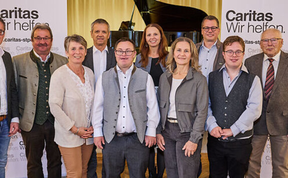 Caritas-Mitarbeiter und Gäste posieren vor einem Klavier in Österreich