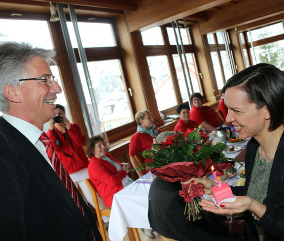 Eine Frau schenkt einem Mann eine Kuchen und Blumen