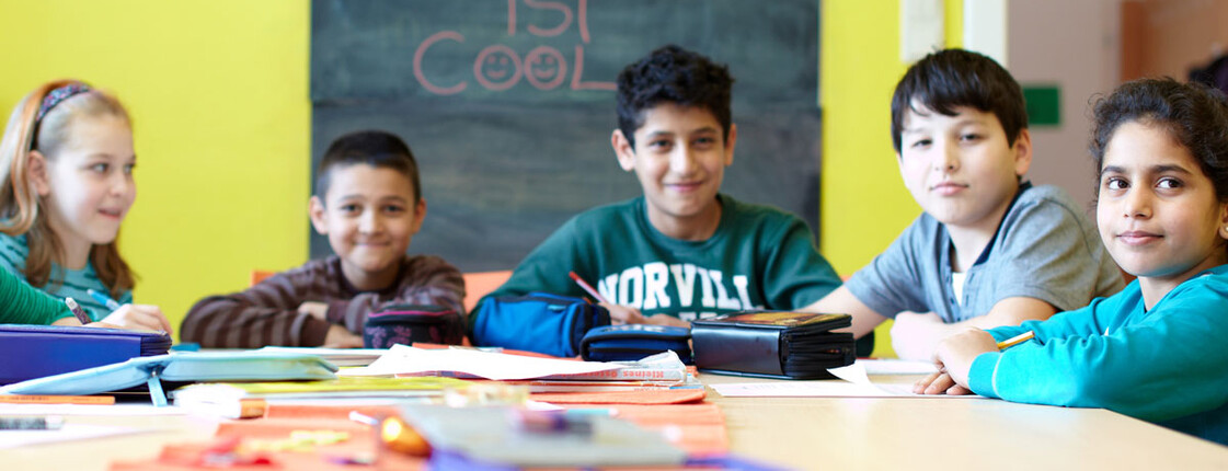 Schulkinder sitzen an einem Tisch und machen Aufgabe