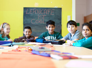 Schulkinder sitzen an einem Tisch und machen Aufgabe