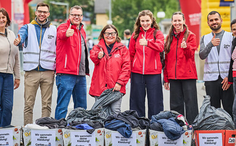 Caritas-Mitarbeiter sammeln Kleidung in Österreich und geben Daumen hoch