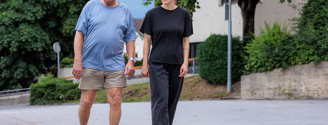 Eine Ehrenamtliche begleitet einen Angehörigen regelmäßig bei Spaziergängen in der Nachbarschaft.