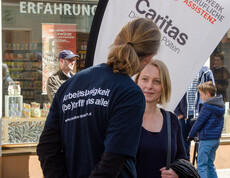 Tag der Arbeitslosen - Caritas Mitarbeiter spricht mit einer Passantin