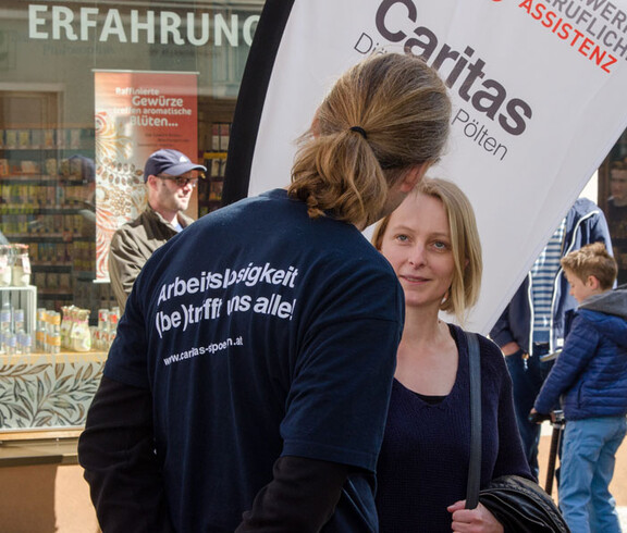Tag der Arbeitslosen - Caritas Mitarbeiter spricht mit einer Passantin
