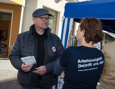 Tag der Arbeitslosen - eine Caritas Mitarbeiterin spricht mit einem Interessierten