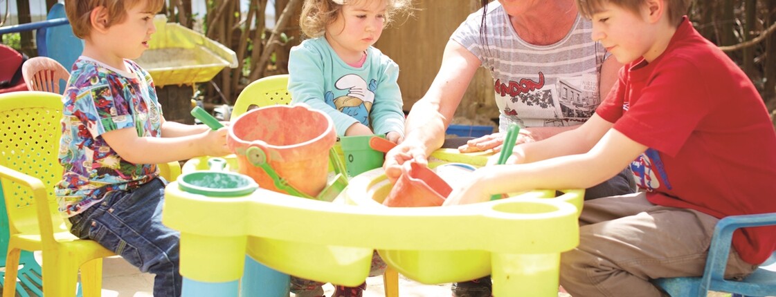 Tagesmutter beim Sandspielen mit Tageskindern