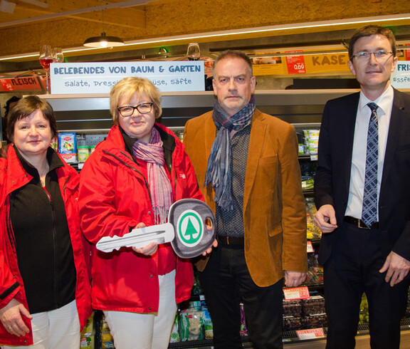 Im Spar Gruppenfoto der Caritas- und Spar-Mitarbeitern mit dem symbolischen Schlüssel für das Caritas-Auto