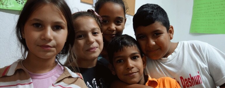Fünf Kinder im Kinderzentrum Eden in Tirana, die fröhlich und eng beieinander stehen und in die Kamera schauen.