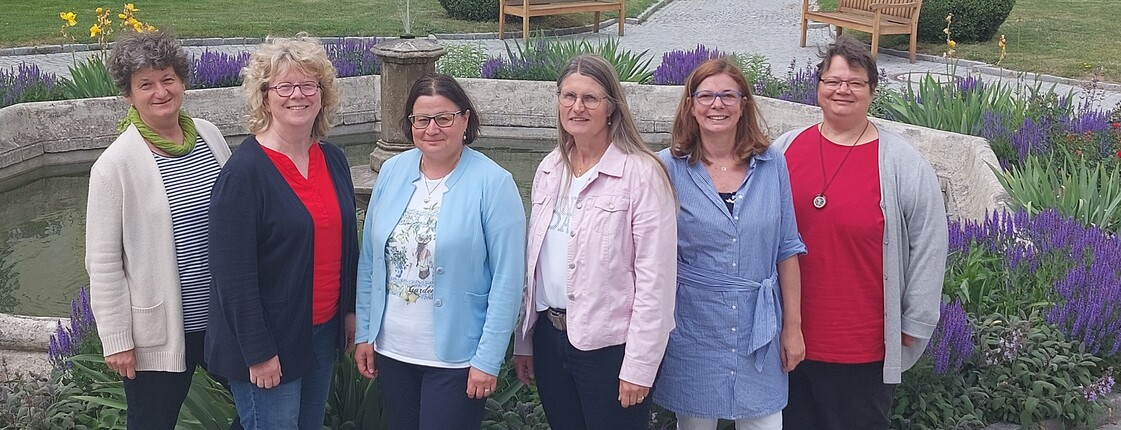 6 Frauen stehen in einer Reihe vor einem Blumenbeet. Sie sind das Team der Pfarrcaritas der Diözese St. Pölten.