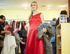 Eine Frau führt einem Publikum die Mode des carla Shops vor.