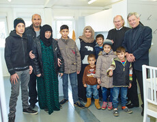 Der Direktor der Caritas St. Pölten und ein Geistlicher mit einer Flüchtlingsfamilie im Containerdorf in Melk