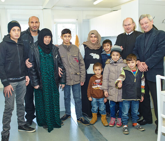 Der Direktor der Caritas St. Pölten und ein Geistlicher mit einer Flüchtlingsfamilie im Containerdorf in Melk
