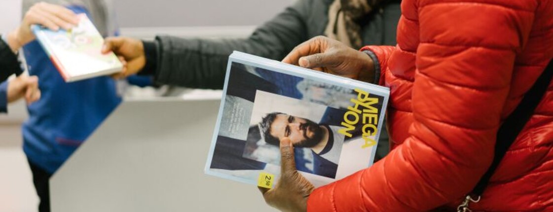 Zwei Frauen verkaufen an einem Tisch die Zeitschrift Megaphon