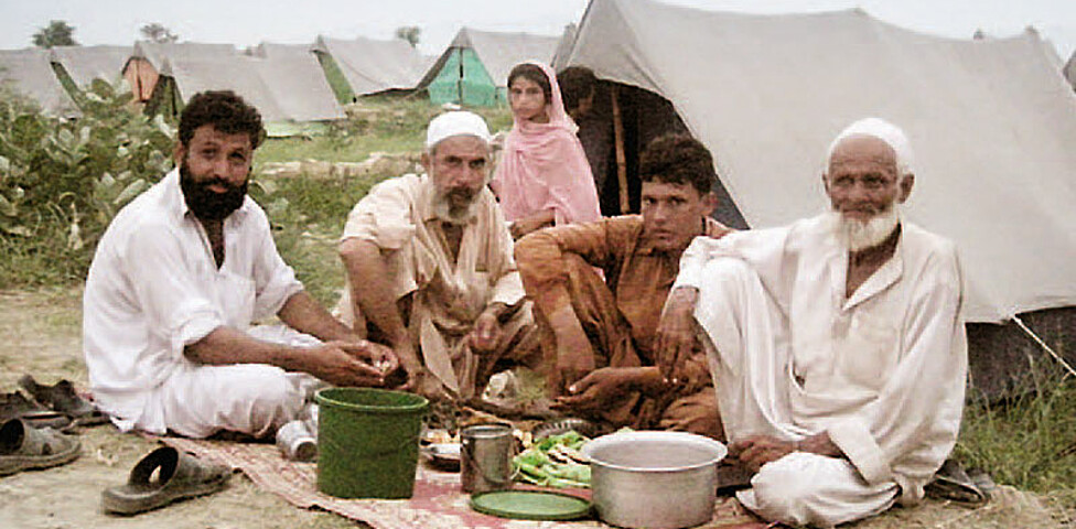 Männer in Pakistan beim Essen in ihrem Zeltdorf