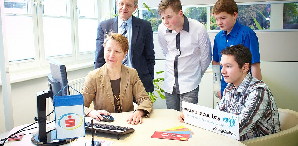 Youngherosday 2015 Sparkasse drei Burschen sehen beim Arbeiten mit dem Computer zu.