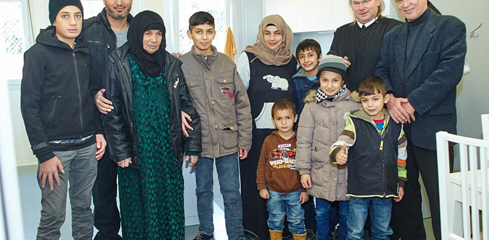 Der Direktor der Caritas St. Pölten und ein Geistlicher mit einer Flüchtlingsfamilie im Containerdorf in Melk