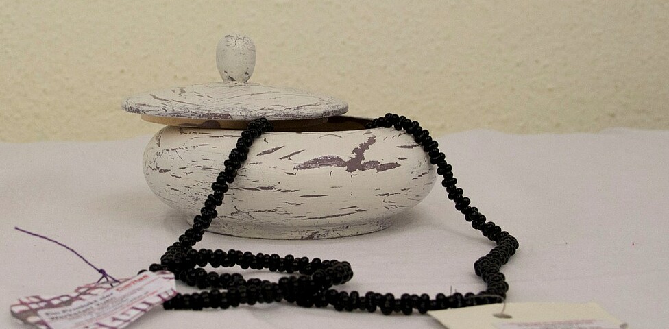 Aus einer Schale hängt eine schwarze Perlenkette heraus
