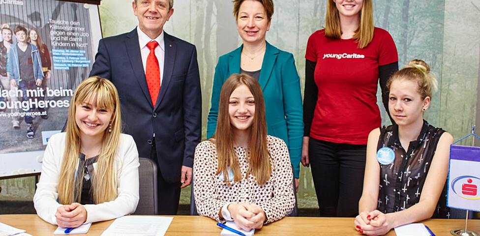 Eine youngCaritas-Mitarbeiterin drei jungen Mädchen und zwei Mitarbeiter in der Sparkassenfiliale Waidhofen an der Ybbs 