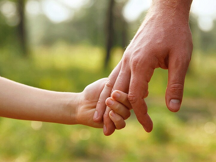 Eine Männerhand hält die Hand eines Kindes.
