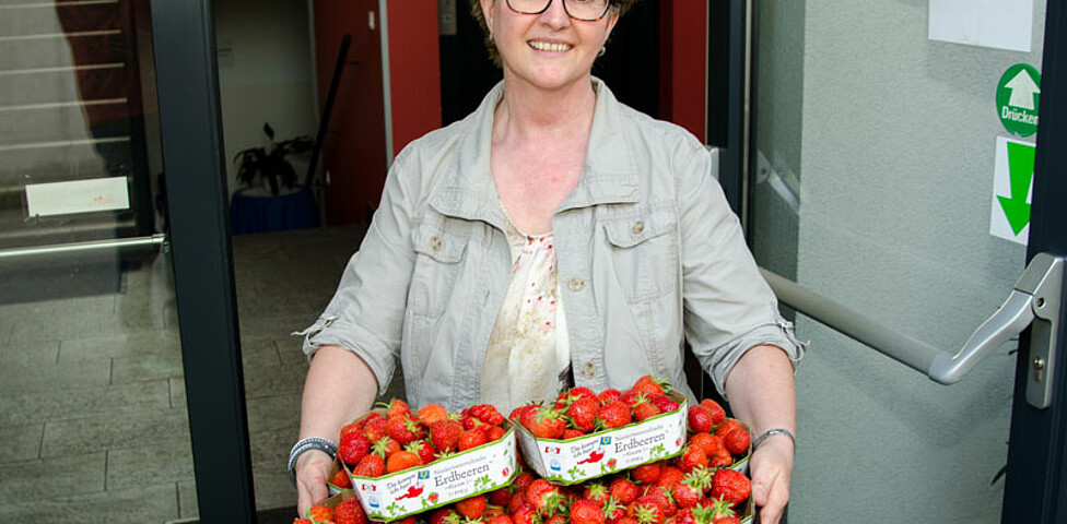 Caritas-Mitarbeiterin mit frischen Erdbeeren