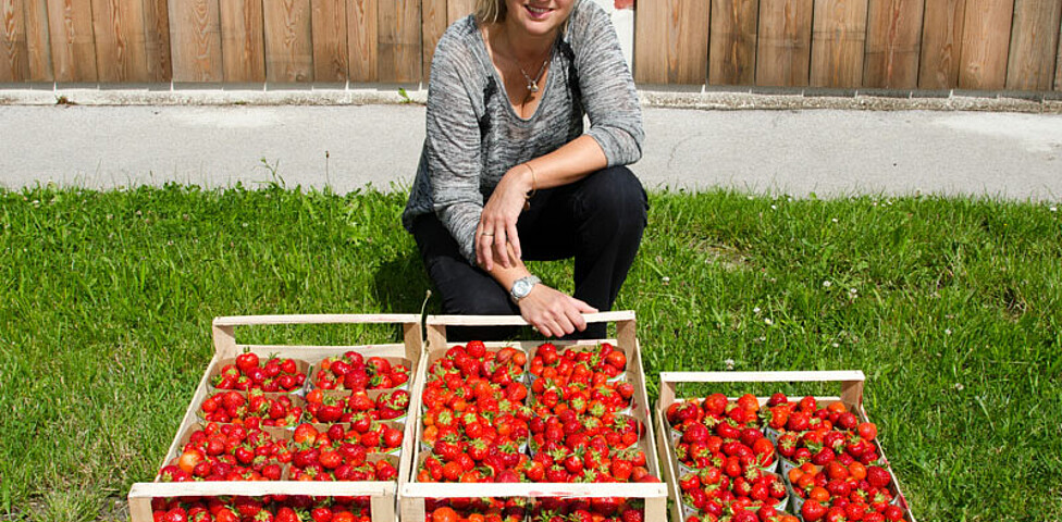 Caritas-Mitarbeiterin mit Kisten voller frischer Erdbeeren